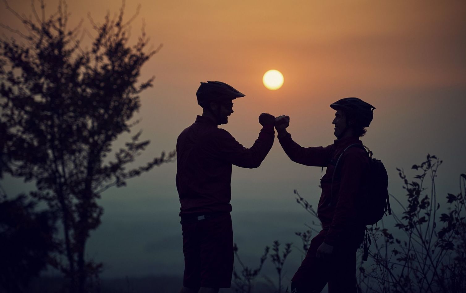 zwei mountainbiker im sonnenuntergang auf dem gipfel