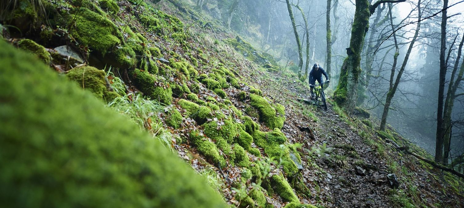 mountainbiker fährt schmalen trail am hang entlang