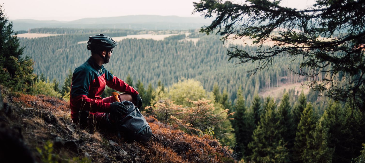 biker sitzt auf einer klippe mit blick ins tal