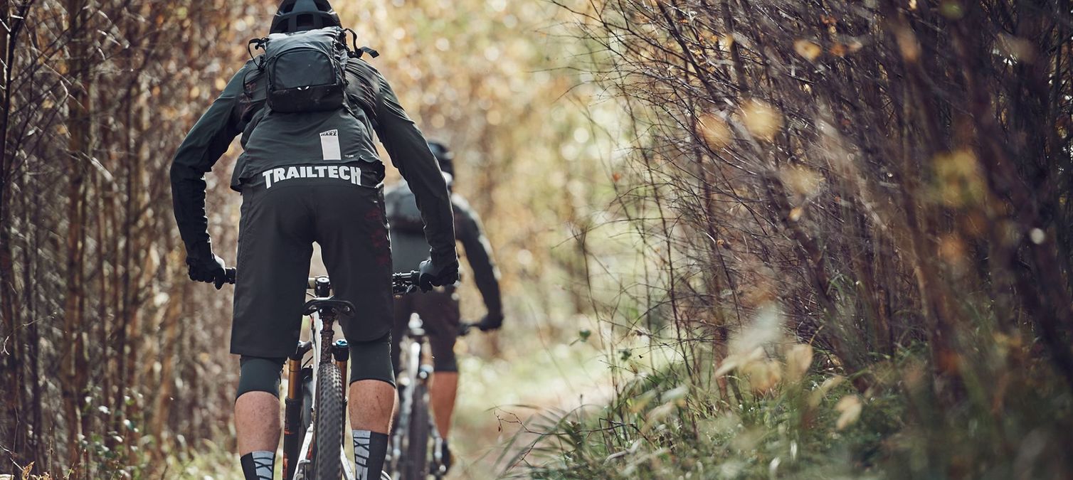 zwei mountainbiker fahren durch dichten wald