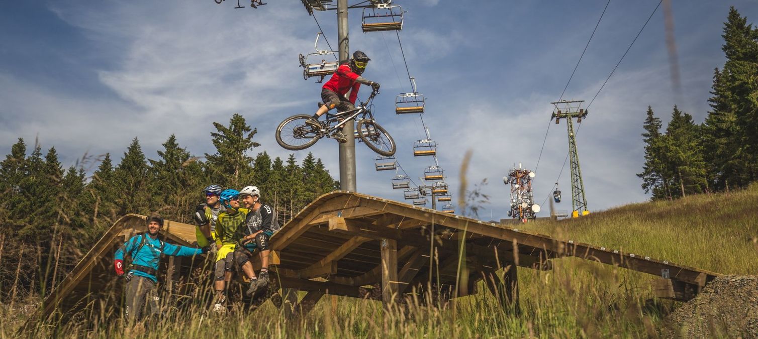 ein mountainbiker springt über eine holzkonstruktion